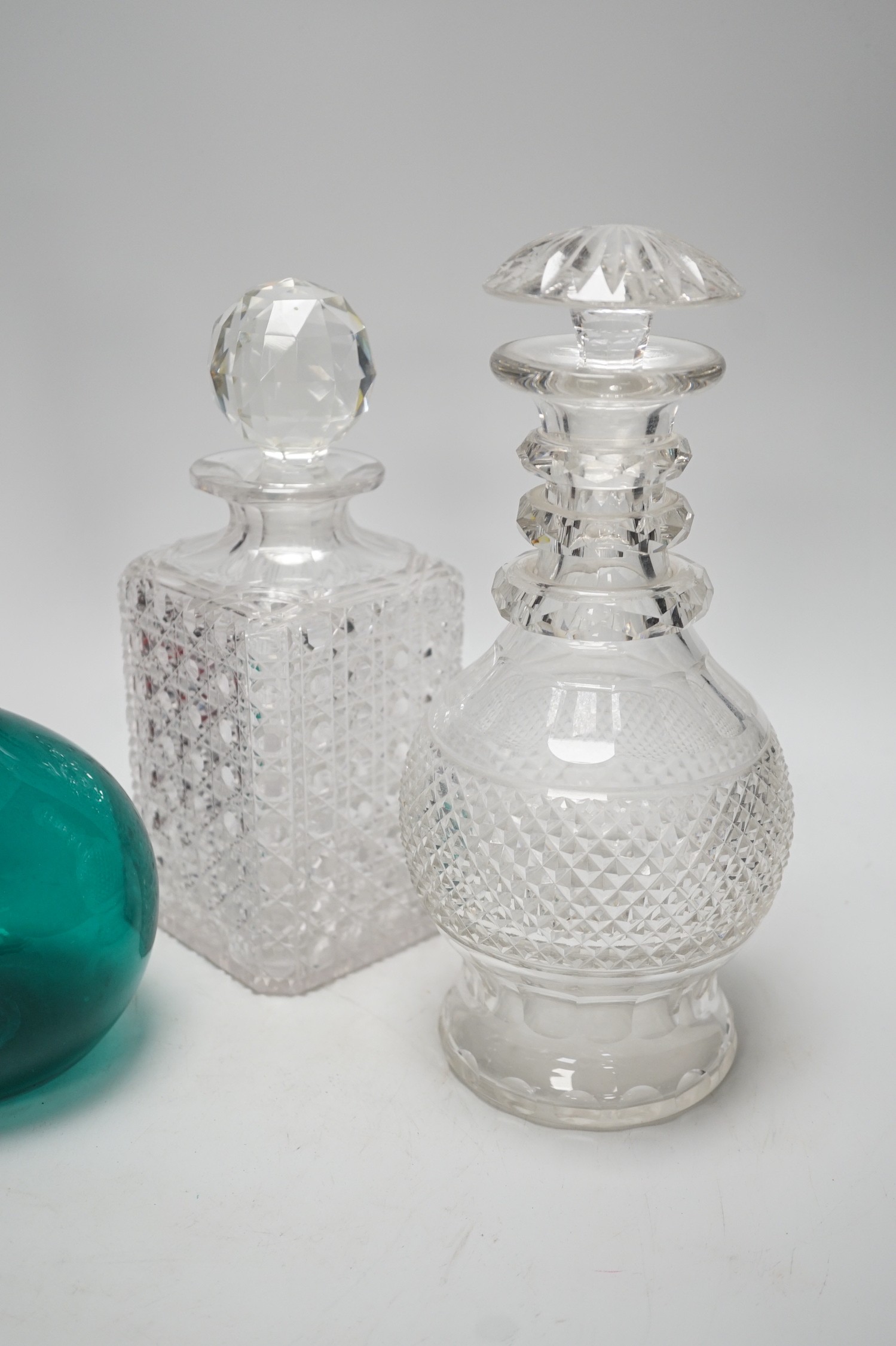 A green glass decanter flagon, a Bohemian red flash cut carafe (lacking stopper), a pineapple cut glass decanter and a square hobnail cut glass decanter (4). Tallest 30cm